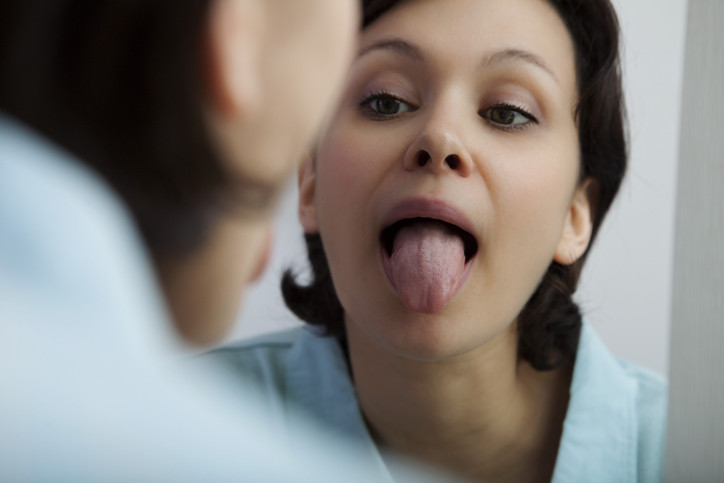 一名棕色头发、棕色眼睛、蓝色衬衫的女人伸出舌头，映在镜子里.jpg